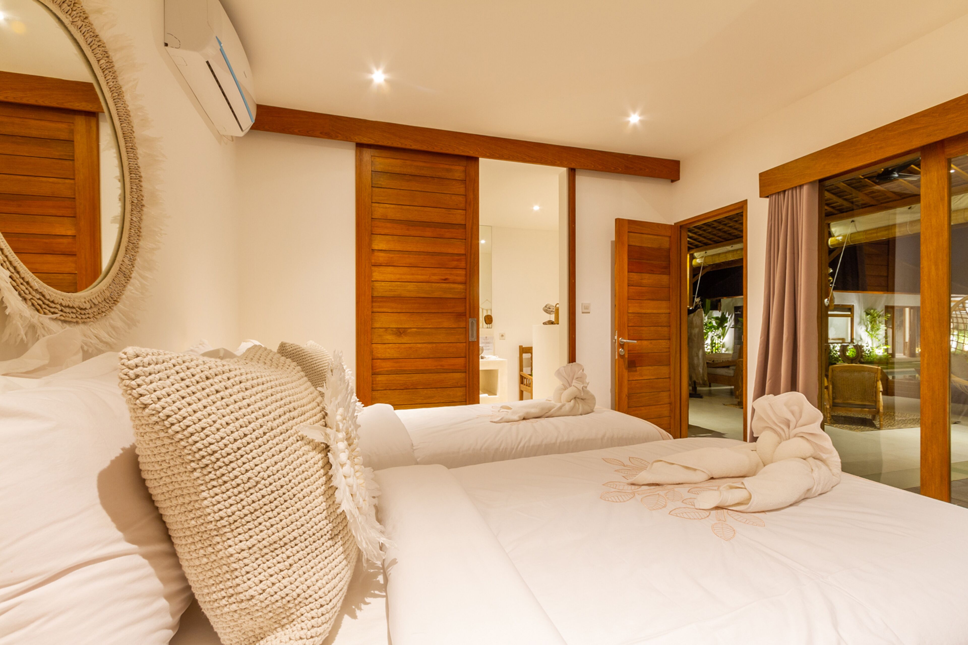 Una camera da letto con due letti, un grande specchio, porte in legno e vista sull'esterno.
