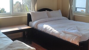 Une chambre avec un grand lit, un lit plus petit et un plancher en bois.