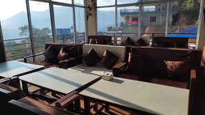 Un restaurant offrant une vue sur les montagnes, avec un espace où l’on peut s’asseoir, comprenant des tables et des bancs rembourrés.