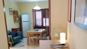 A hallway leading to a dining area with a table and chairs, a fan, and a vase of artificial flowers. - VILLA CECILIA/ap. 2: mid in the nature and close to  golden Cilento beaches (Pisciotta)