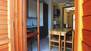 A kitchen with a dining area, wooden cabinets, a microwave, and a sink. - VILLA CECILIA/ap. 2: mid in the nature and close to  golden Cilento beaches (Pisciotta)