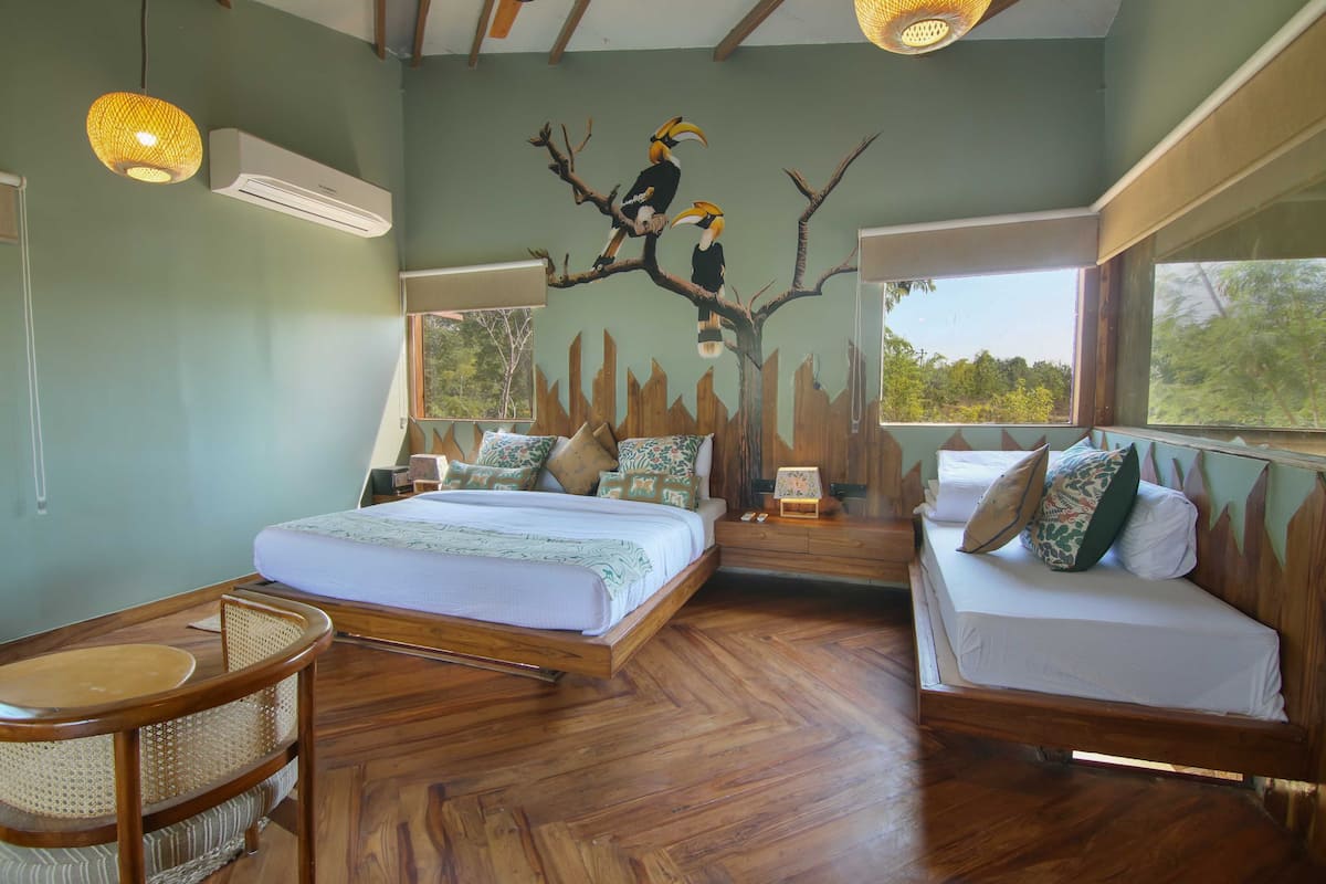 A room with two beds, a wooden floor, a wall mural, and a window.
