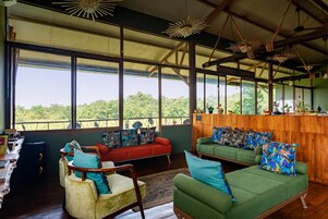 Una habitación amplia con ventanas grandes, techo de madera y vistas al exterior.