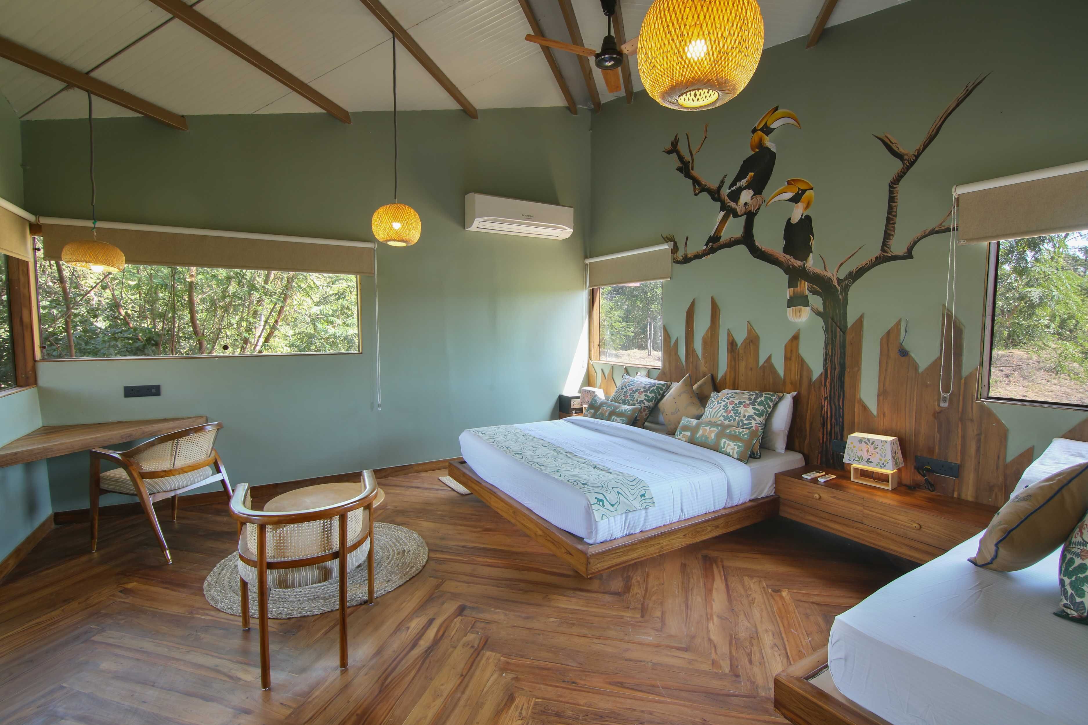 A spacious bedroom with a large bed, wooden furniture, and a mural of birds on the wall.