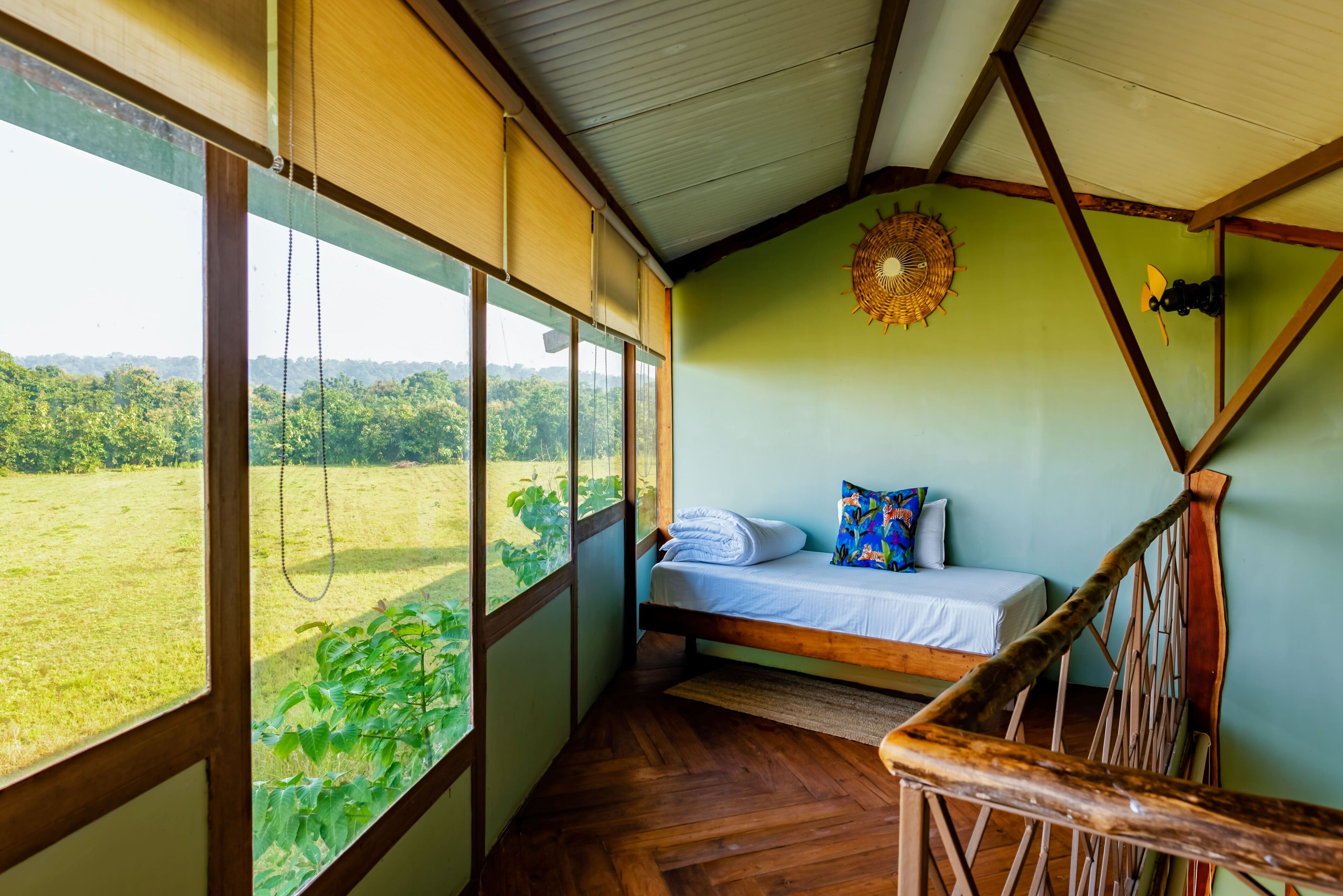 Una stanza con un letto, vista su un campo verde e travi in legno al soffitto.