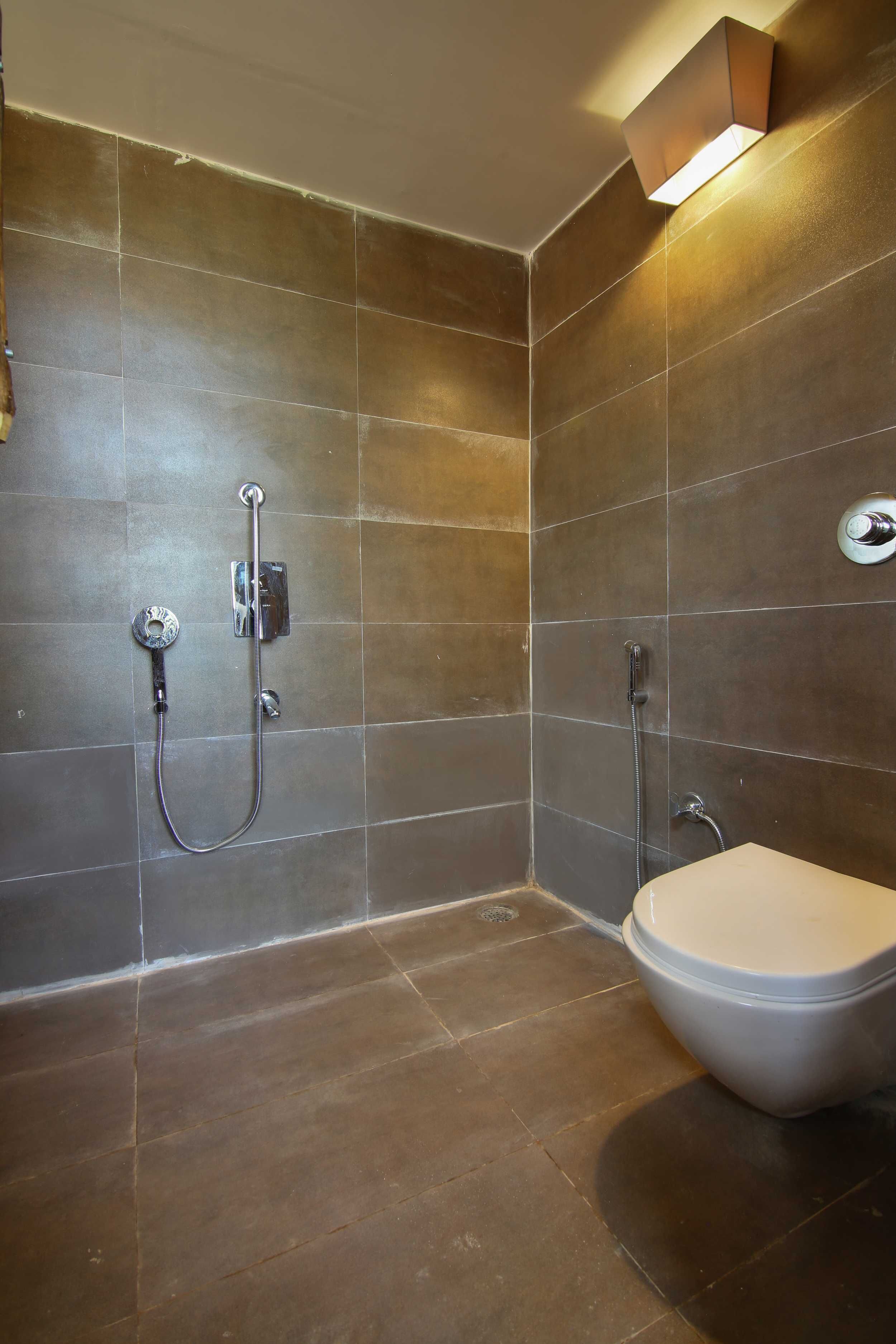 Une salle de bain moderne équipée d’une douche, de toilettes et d’un luminaire fixé au mur.