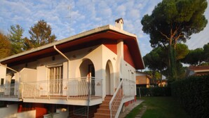 A two-story house with a red roof, white walls, and a balcony with white railings.