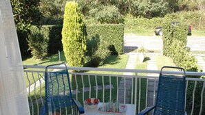 A balcony with two blue chairs and a small table with drinks and snacks.