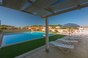 A swimming pool with a pergola overhead, lounge chairs, and a view of the surrounding landscape. - Stylish Residence Le Fontane 1 Bedroom Apartment Sleeps 3 (Villasimius)