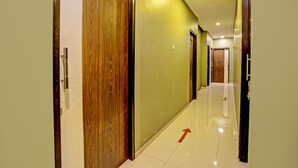 Un pasillo de hotel con puertas de madera, suelo de baldosas y una flecha direccional.