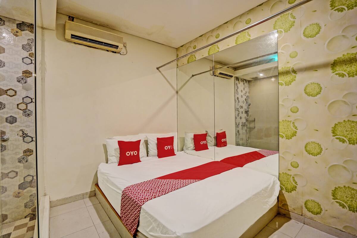 A hotel room with a large bed, a mirror, and a shower.
