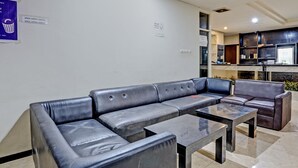 Un espacio de sala moderno con un sofá de cuero, una mesa de centro y una cocina al fondo.