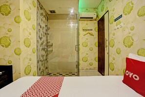 Une chambre d’hôtel avec un lit, une douche et un mur orné d’un motif vert et blanc.