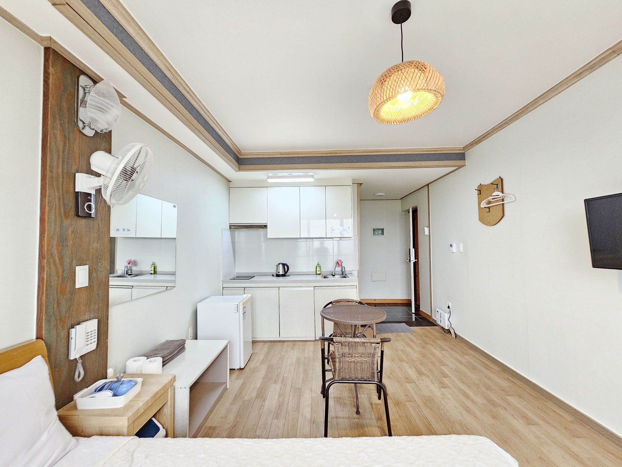 A compact hotel room with a kitchenette, a dining area, and a bed.
