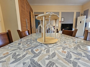 A dining table with a patterned tablecloth, wooden chairs, and a decorative centerpiece. - Red Castle Pension (Jeju City)