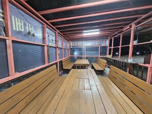 Un espace extérieur abrité, doté de bancs et de tables en bois, et caractérisé par un design simple et fonctionnel.