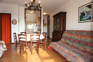 A dining area with a table and chairs, a sofa, a chandelier, and a cabinet.