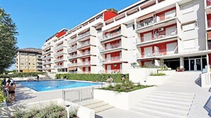 Un hôtel à plusieurs étages doté de balcons, d’une piscine et d’un jardin aménagé.