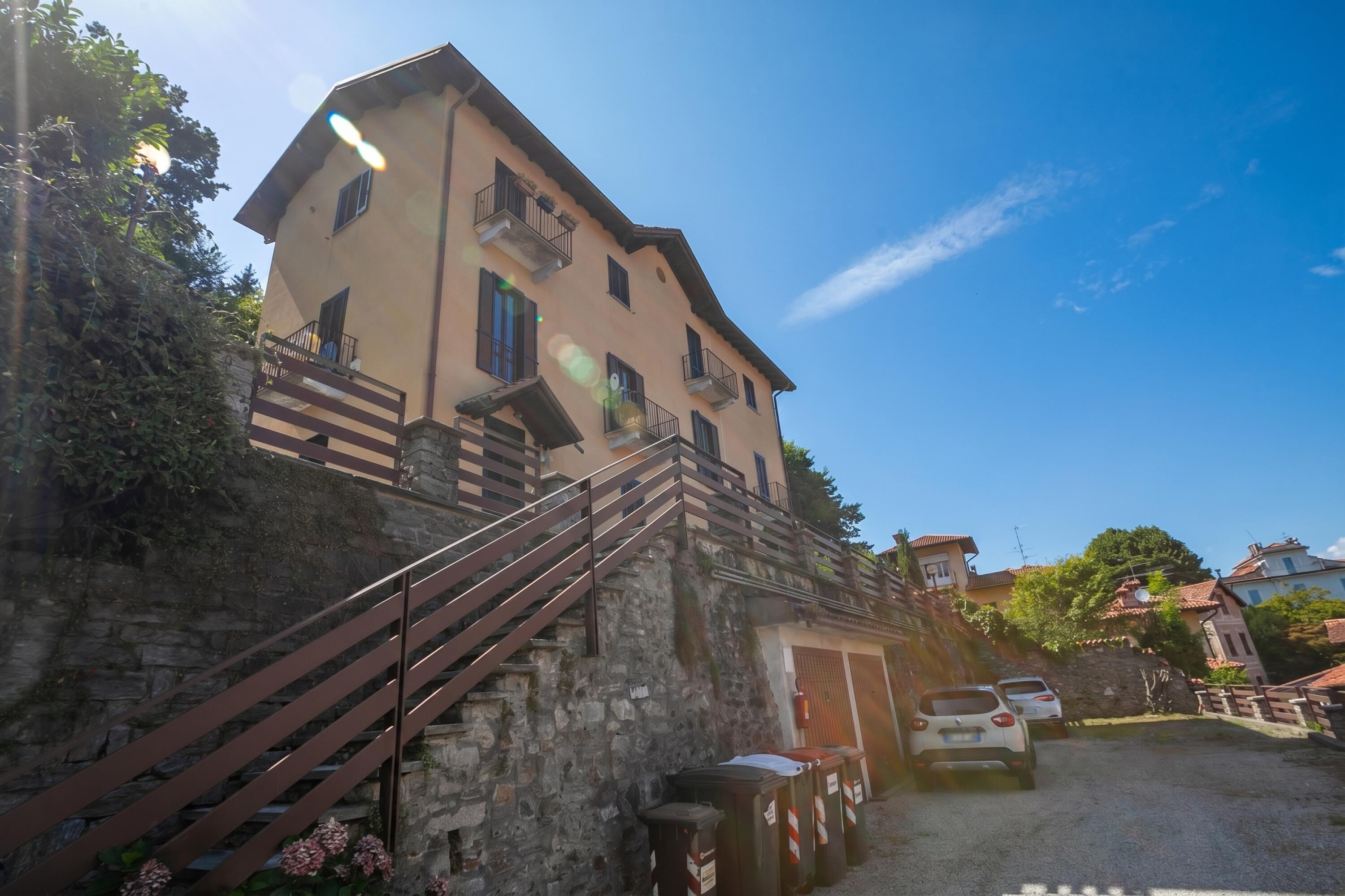 A building with a stone staircase, a door, and parked cars.