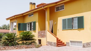 A yellow building with green shutters, a stone wall, and a staircase leading to the entrance. - Villa 'Casa Antonietta' with Private Terrace and Shared Garden (Sant'Anna Arresi)