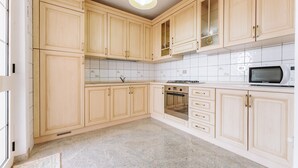 A kitchen with wooden cabinets, a microwave, an oven, and a tiled backsplash. - Villa 'Casa Antonietta' with Private Terrace and Shared Garden (Sant'Anna Arresi)