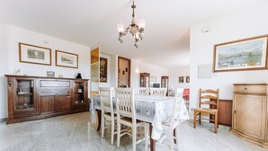 A dining area with a table set for four, wooden chairs, a chandelier, and framed artwork on the walls. - Villa 'Casa Antonietta' with Private Terrace and Shared Garden (Sant'Anna Arresi)
