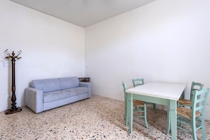 A room with a sofa, a table with chairs, a floor lamp, and a wall socket. - Holiday Home 'L'ulivo Di Alice' with Shared Terrace and Wi-Fi (Trapani)