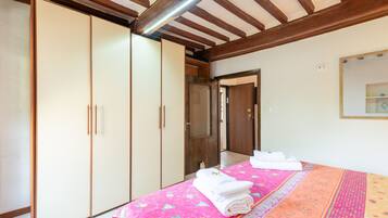 A bedroom with a bed, a wardrobe, a mirror, and a door leading to another room.