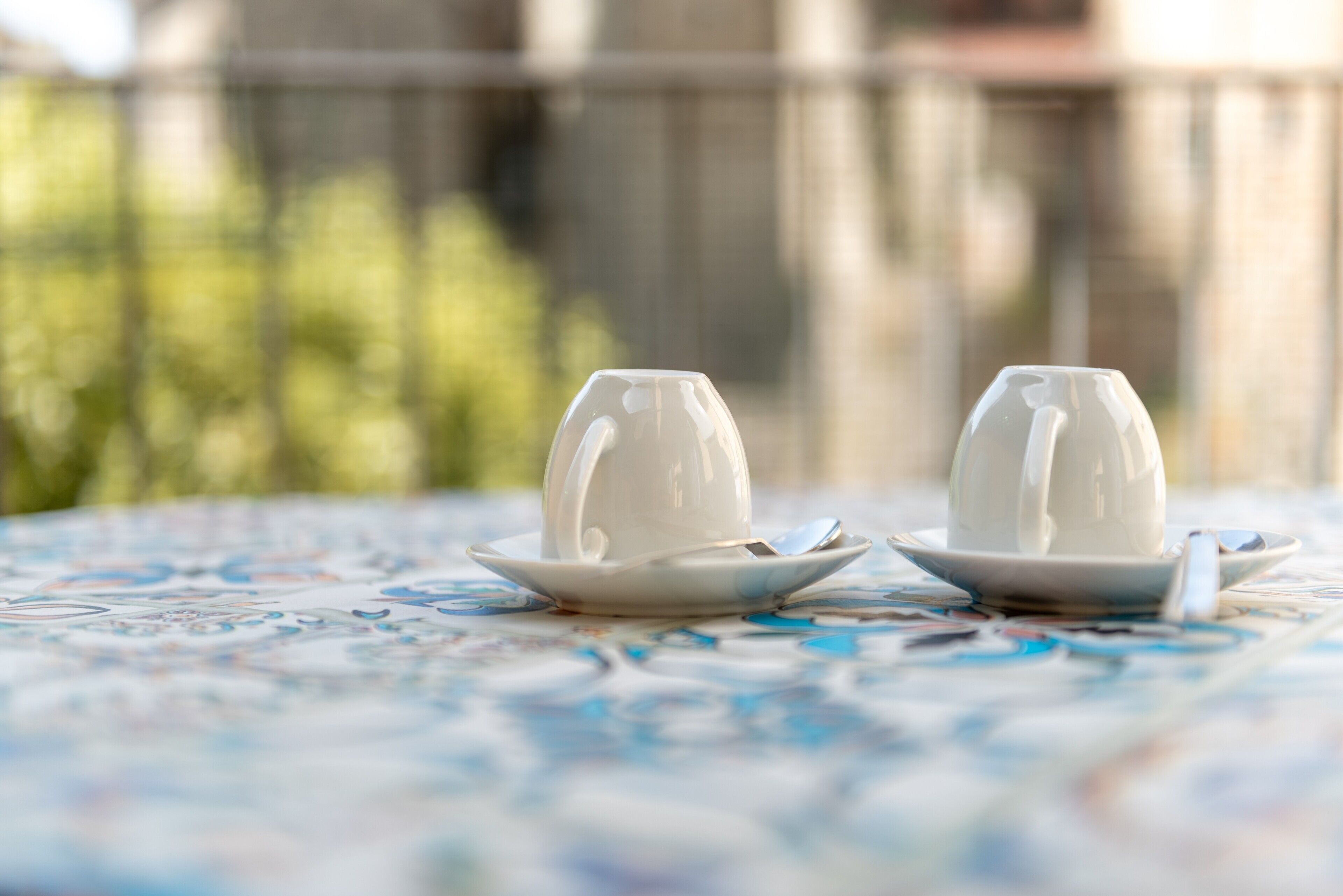 Two white cups on saucers on a table with a floral pattern.