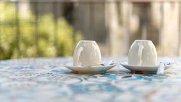 Two white cups on saucers on a table with a floral pattern.