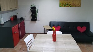 Una cocina con una mesa de comedor, sillas, un sofá con cojines con forma de corazón y un cuadro en la pared.
