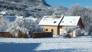 Un paysage enneigé avec un bâtiment doté d’un toit en pente et d’un petit porche.