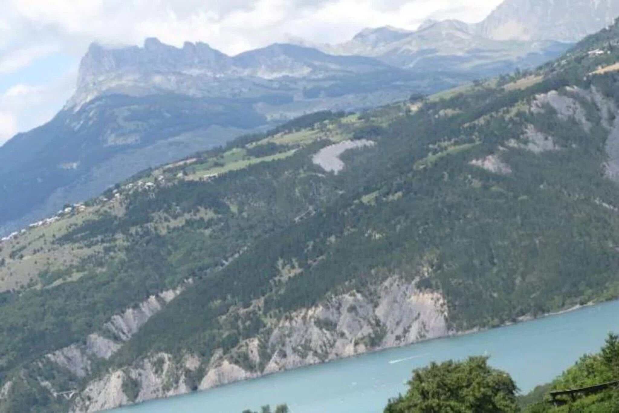 Un paisaje montañoso con un lago, un pequeño asentamiento y un cielo despejado.