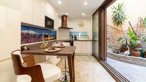 A modern kitchen with a dining area, a large window, and a decorative wall piece. - Apartment 'Plaisir Des Pierres' with Private Terrace and Wi-Fi (RIVESALTES)