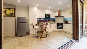 A modern kitchen with a refrigerator, a dining table with chairs, and a large window. - Apartment 'Plaisir Des Pierres' with Private Terrace and Wi-Fi (RIVESALTES)