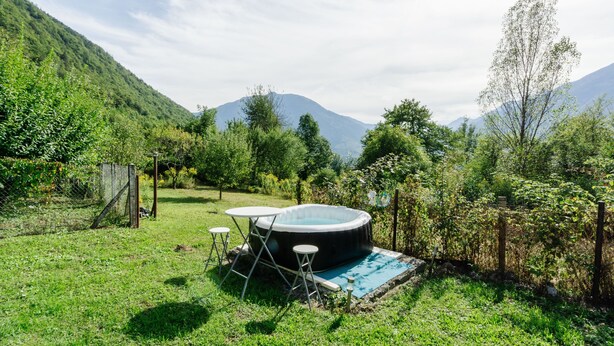 Un bain à remous extérieur, installé dans un espace verdoyant, avec une montagne en toile de fond.