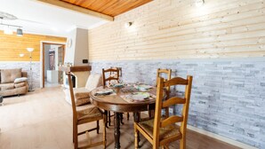Un espace repas avec une table et des chaises en bois, un mur en briques et un plafond en bois.