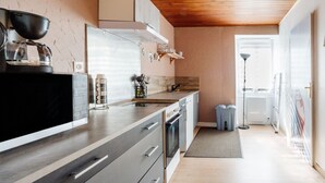 Une cuisine moderne avec un plafond en bois, une machine à café et un four encastré.