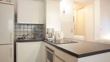 A modern kitchen with white cabinets, a black countertop, a coffee maker, and a microwave.
