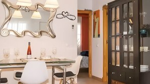 A dining area with a glass table, chairs, a wine bottle, and a decorative mirror. - 'Bahía D'Or Plaza' Apartment with Air Conditioning (Chiclana de la Frontera)