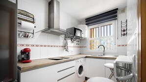 A compact kitchen with a washing machine, a coffee maker, and a microwave. - 'Bahía D'Or Plaza' Apartment with Air Conditioning (Chiclana de la Frontera)