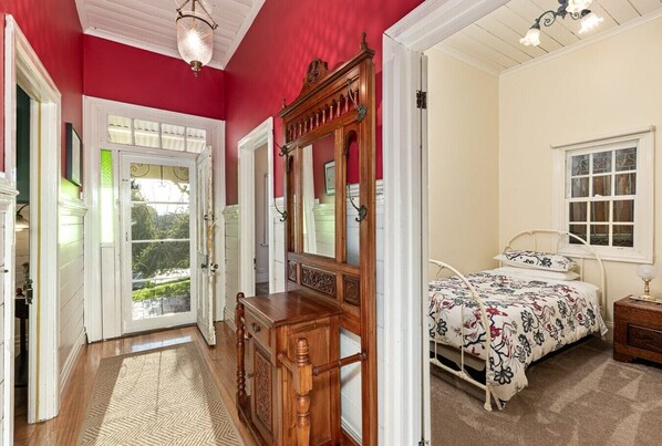 Een slaapkamer met een bed, een dressoir, een spiegel en een raam.