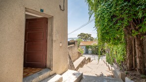 A stone staircase leading to a door, a building with a tiled roof, and a view of a tree and a distant building.