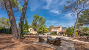 A residential property with a patio area, outdoor seating, and a large house with a tiled roof.