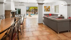 A spacious living area with a dining table, a gray sofa, and a fireplace.