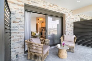A balcony with wicker furniture, a round table, and a view into the interior.