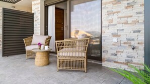 A modern outdoor seating area with wicker furniture and a stone wall. - Apartment 'Ionian Sea View Luxury Apartments' with Wi-Fi and Air Conditioning (Lefkada)