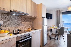 A modern kitchen with wooden cabinets, a tiled backsplash, a built-in oven, and a dining area with a view.