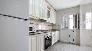 A kitchen with white cabinets, a microwave, an oven, and a tiled backsplash. - Vacation Home 'Luha' with Private Terrace and Wi-Fi (Corralejo)