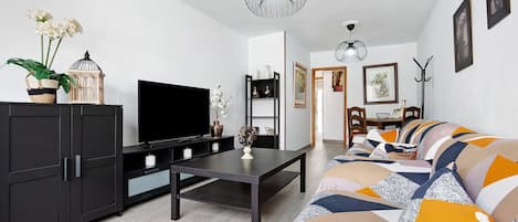 A modern living room with a sofa, TV, and decorative items.